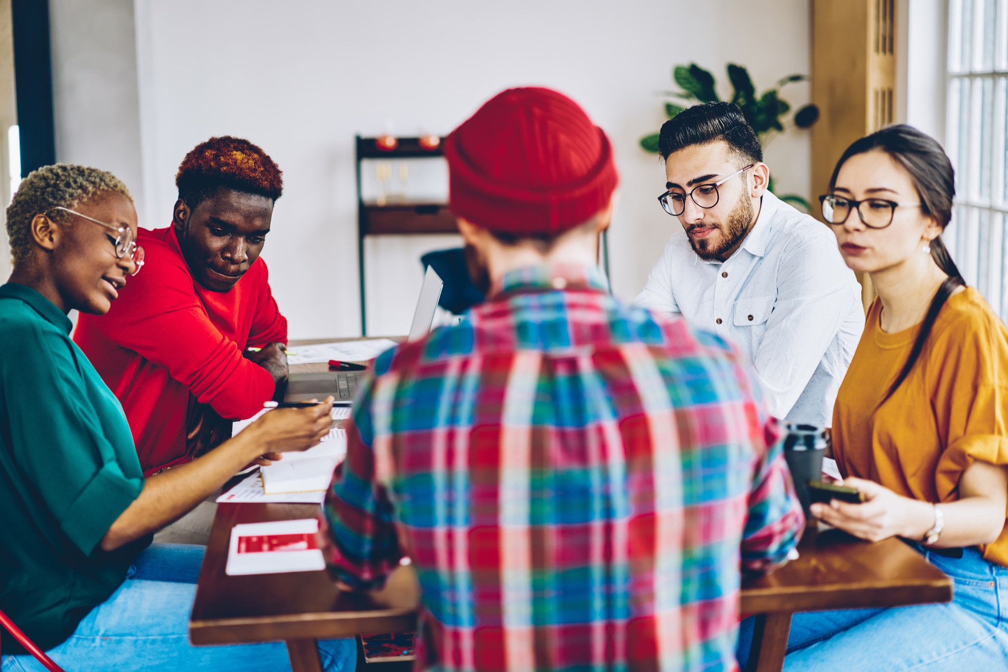 Professional creative designers working in team for doing project plan, multiracial crew discussing ideas at meeting table in coworking space, young leaders having conference about business